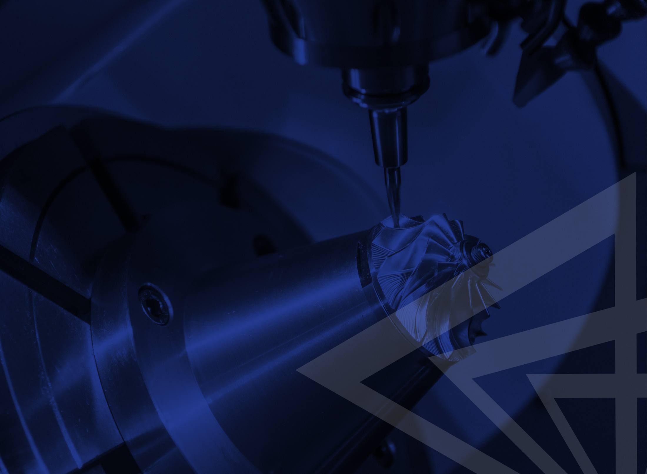 A blue-toned photo of a five-axis machine milling an impeller